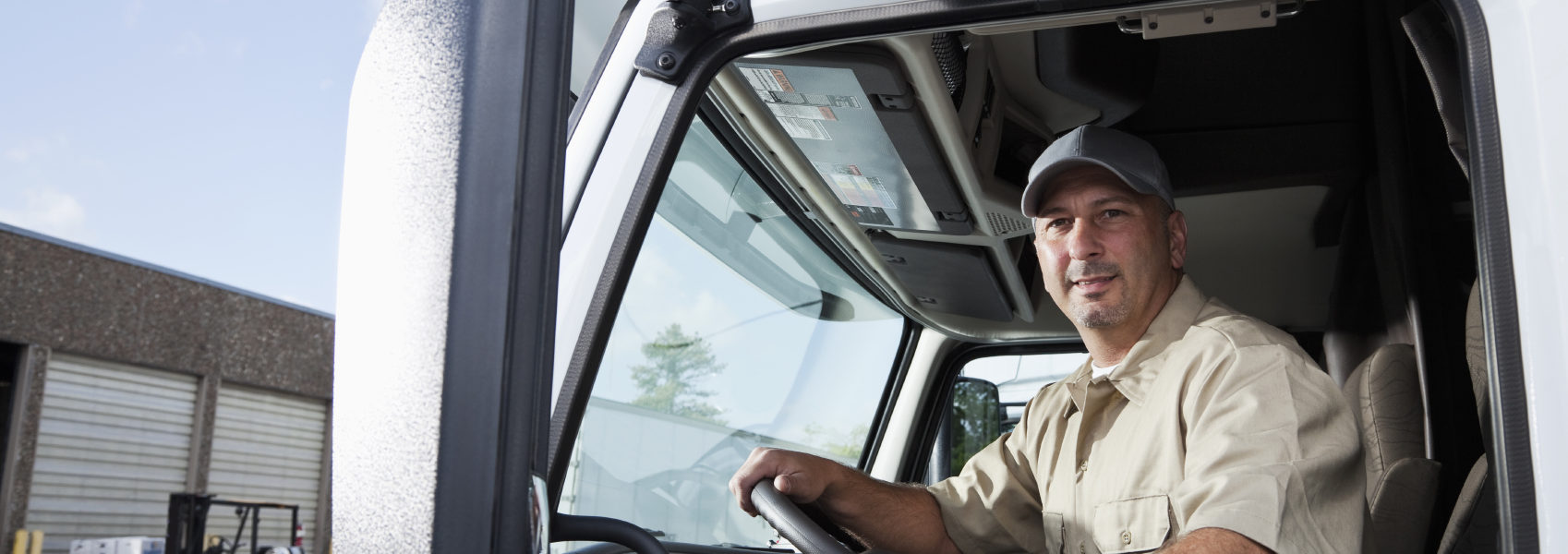 Truck driver sitting in cab of semi-truck Truck driver (30s) sitting in cab of semi-truck.